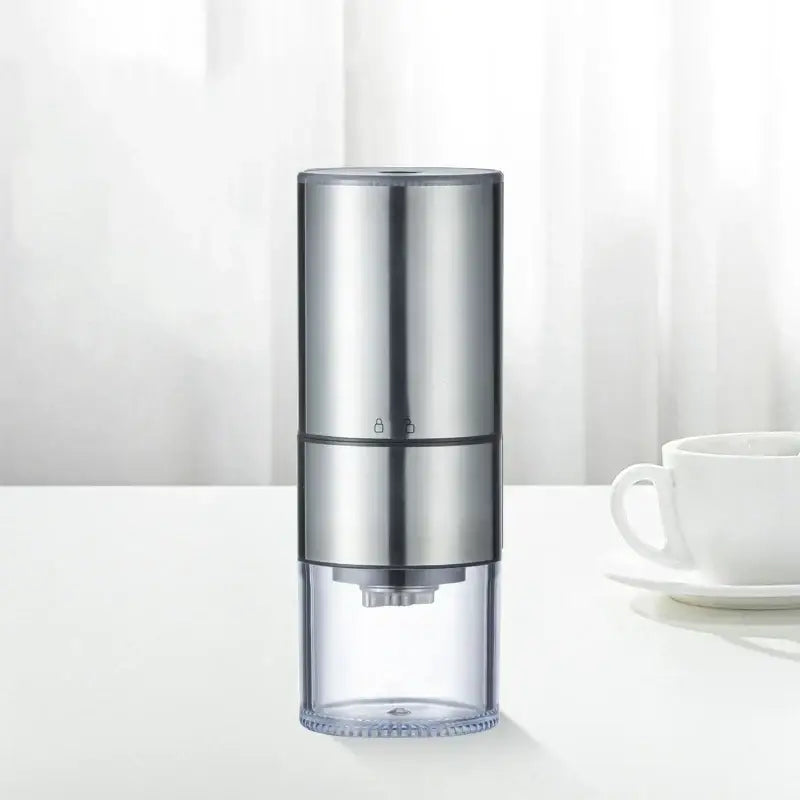 Silver electric bean grinder with transparent base and two-tone metallic body for modern kitchen use