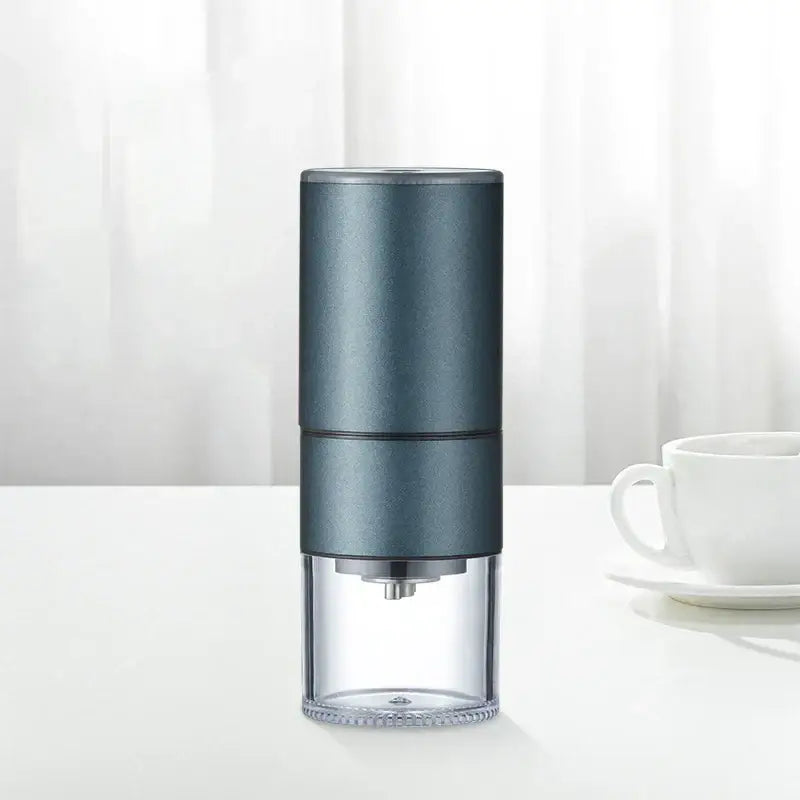 A sleek dark gray modern matte electric bean grinder with a transparent collection base for kitchen coffee use