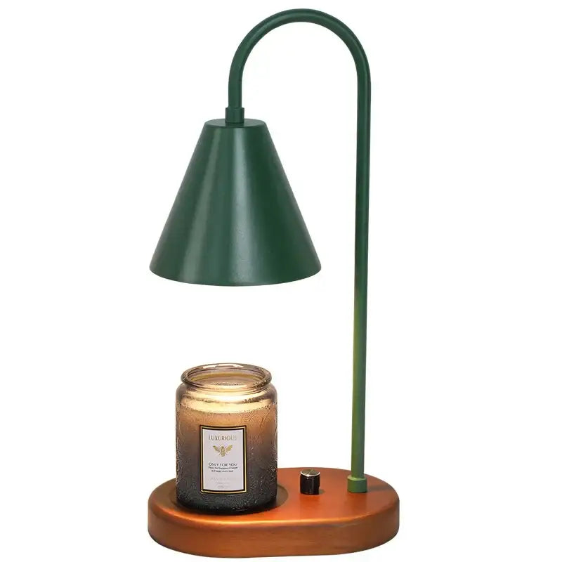 Modern matte green electric candle lamp warmer with dark green metal bell shade and wooden base over amber candle jar