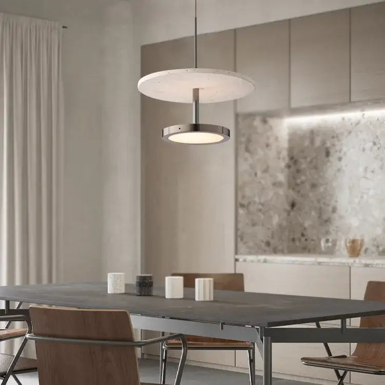 Modern matte white and brushed metal led chandelier black stone pendant suspended above a dining table by decorbites