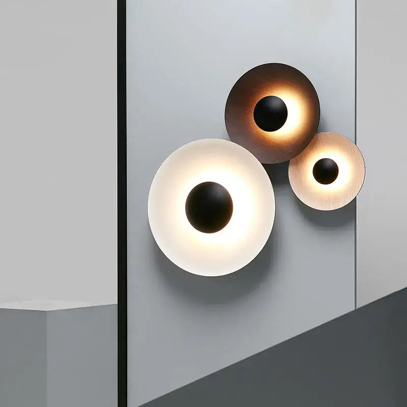 Three modern matte white and brushed bronze ginger round wall lamps with frosted diffusers and dark central accents