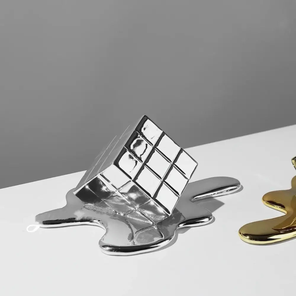 Shiny silver metallic sculpture of a melting cube with grid lines as decorbites geometric gold resin living room decor