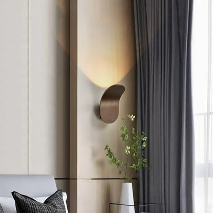 Modern metal bracket wall light in black gold coffee finish with sleek bronze-toned curved design casting warm light