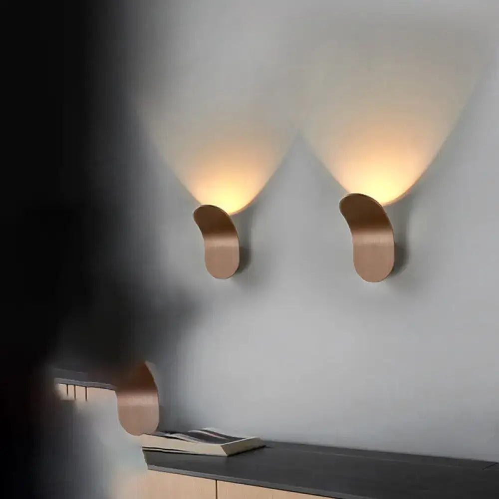 Modern metal bracket wall light in copper finish with sleek curved design casting warm light for bedroom use