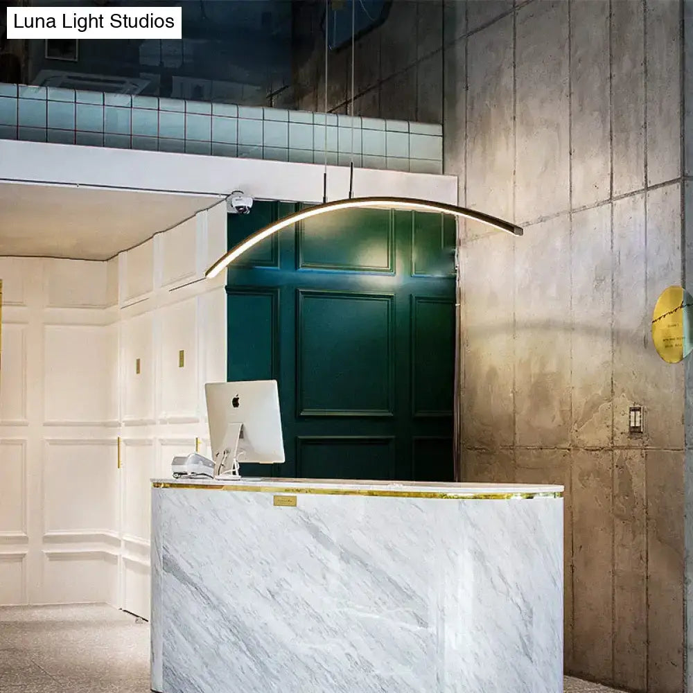 A sleek metallic arc shape led pendant light hangs above a marble dining room reception desk