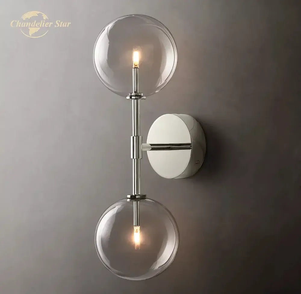 Modern chrome finished wall sconce with two clear glass globe shades for bedroom lighting and decor