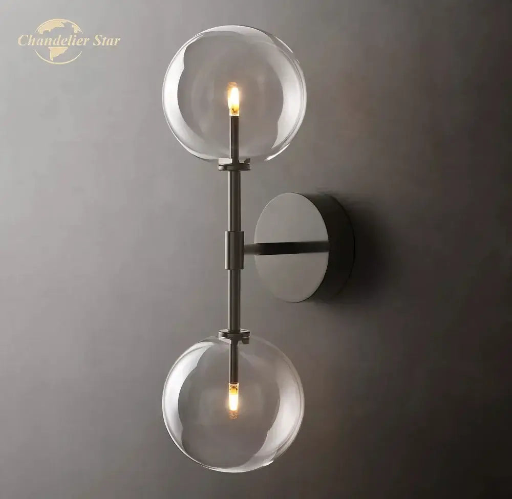 Modern metallic wall sconce featuring two clear glass globe bulbs with a sleek metallic finish for bedroom lighting