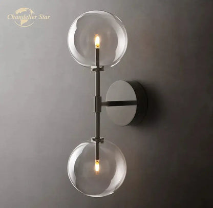 Modern metallic wall sconce featuring two clear glass globe bulbs with a sleek metallic finish for bedroom lighting