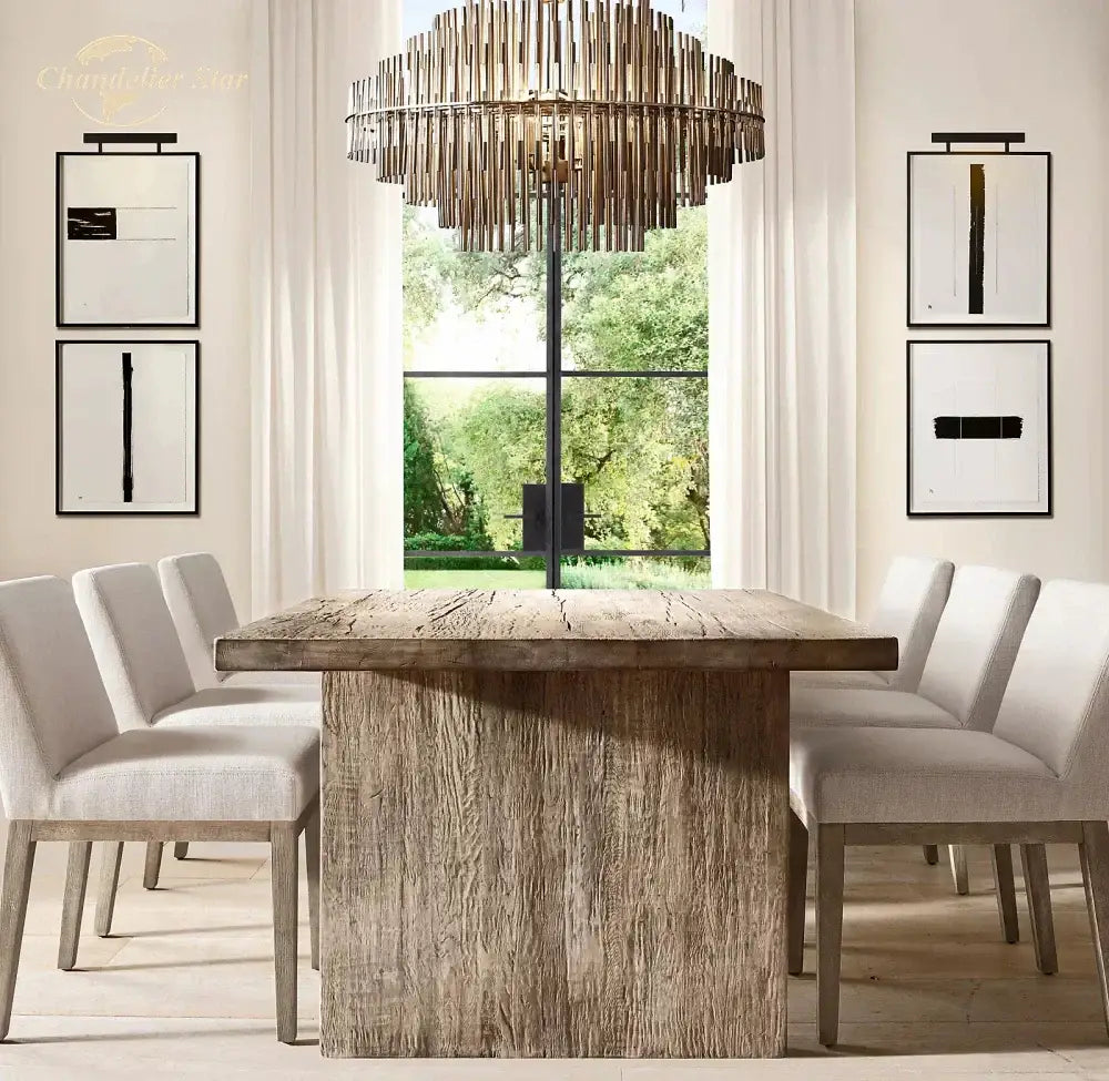 Rustic wooden dining table with thick textured surface and sturdy legs under modern metallic emile round led chandelier