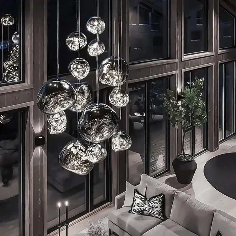 Modern metallic glass pendant lights with reflective finish hang in an elegant dining room cluster fixture