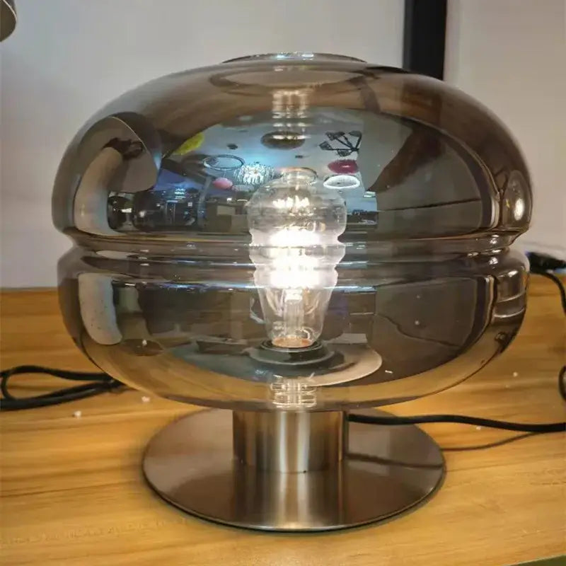A sleek dome-shaped metallic table lamp with a reflective finish and exposed bulb for elegant bedroom table lighting