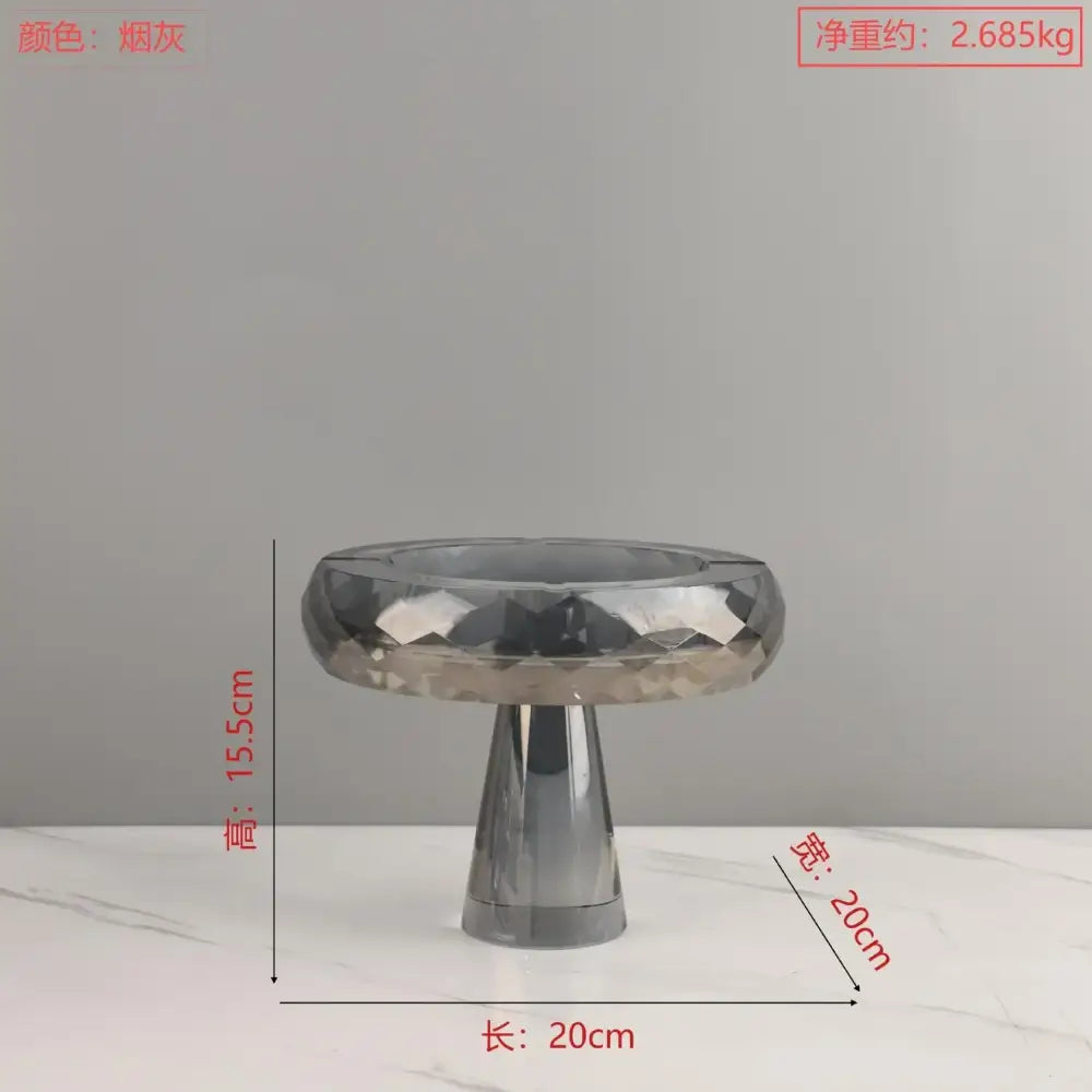 A sleek smoke-gray metallic geometric glass fruit bowl stand with faceted diamond top and tapered pedestal base for decorbites