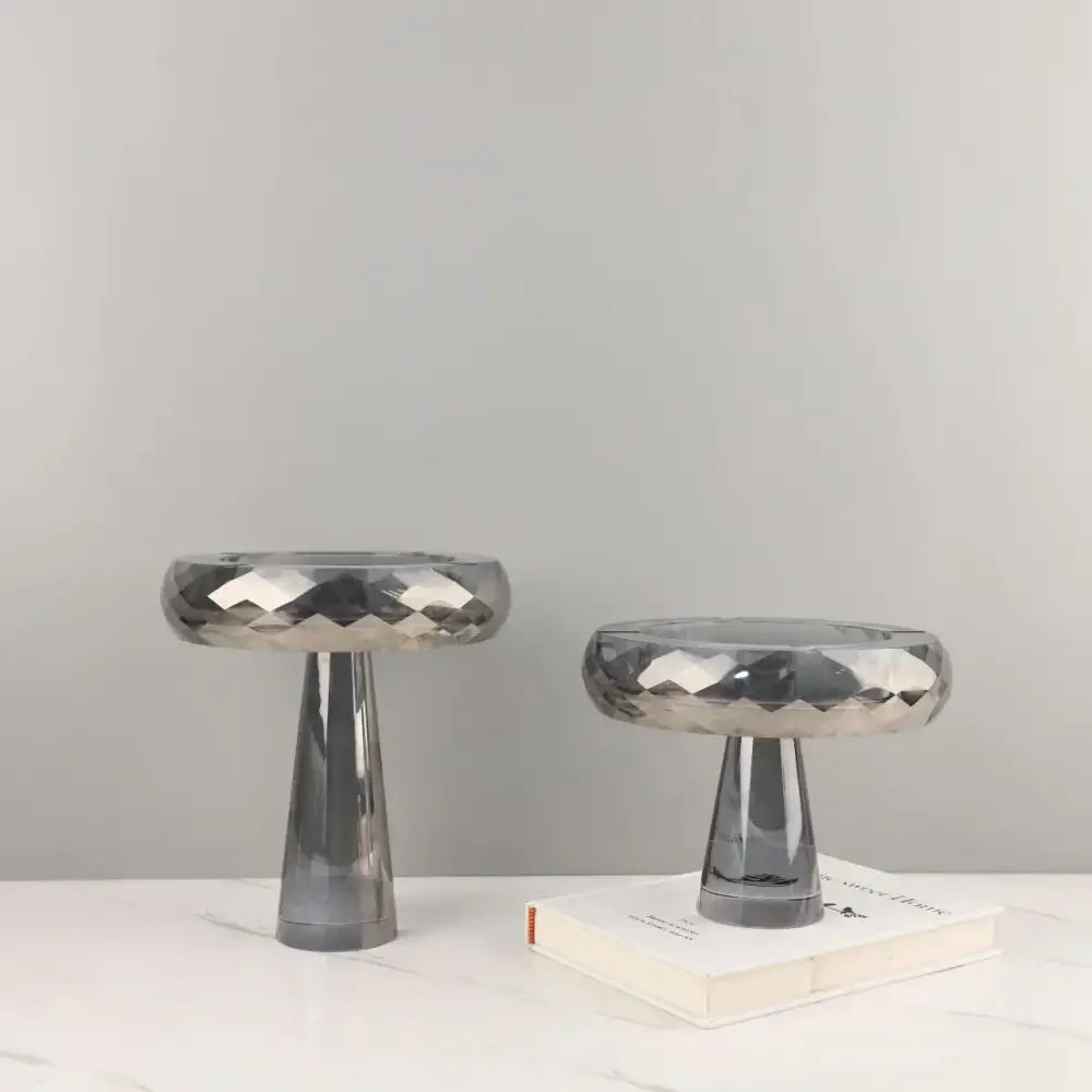 Two sleek modern metallic silver geometric glass fruit bowl stands with faceted finish and tapered cylindrical bases