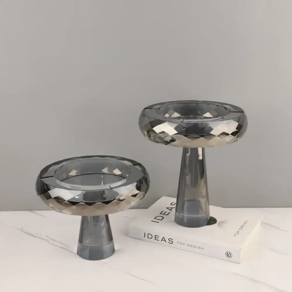 Two sleek dark gray glass candle holders with faceted stems complement decorbites geometric glass fruit bowl dining room stand