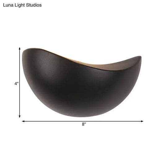 A sleek matte black ceramic bowl with a crescent shape used in modern metallic wall washer bedroom sconce lighting