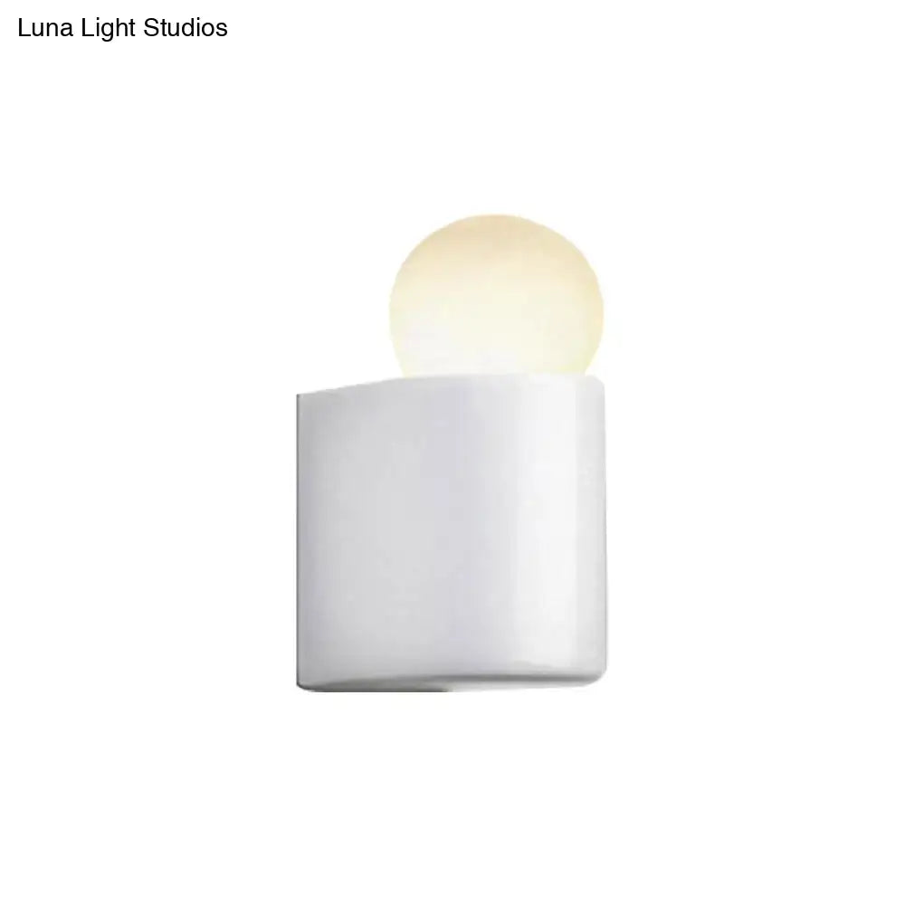 White cylindrical milk glass wall lamp with softly glowing spherical bulb for small medium bedroom use