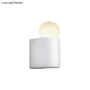 White cylindrical milk glass wall lamp with softly glowing spherical bulb for small medium bedroom use