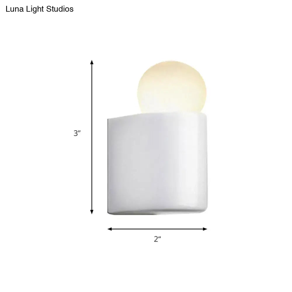 Modern small medium wall lamp with white milk glass cylindrical base and warm glowing spherical bulb for bedroom use