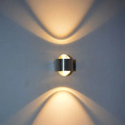 Modern minimalist aluminum led wall lamp with sleek metallic finish and warm focused lighting casting curved shadows