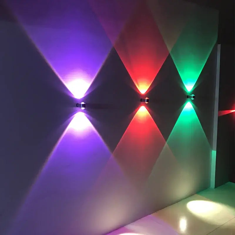 Three modern led wall lamps with sleek black light aluminum sconces casting vibrant purple red and green patterns