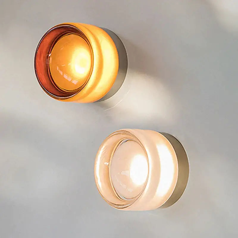 Two modern wall sconces with frosted glass shades and decorbites amber jelly led emitting amber and cream light