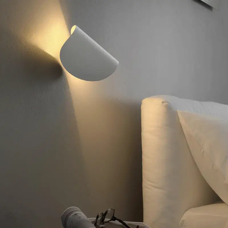 A sleek white minimalist wall lamp with curved art decor rotating design casting warm light for bedroom decorbites