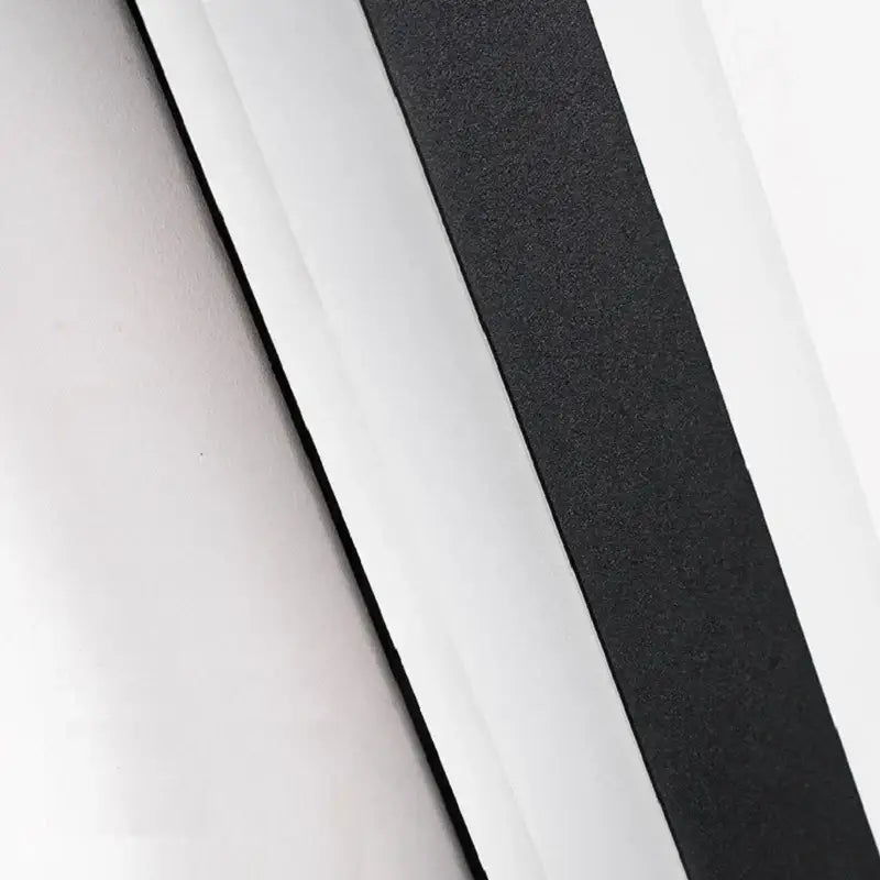 Black textured adhesive strip on the back side of a modern minimalist black aluminum waterproof led outdoor wall lamp