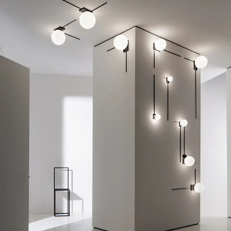 Modern minimalist black wall lights featuring spherical white glass ball globes and sleek metal arms for bedroom use