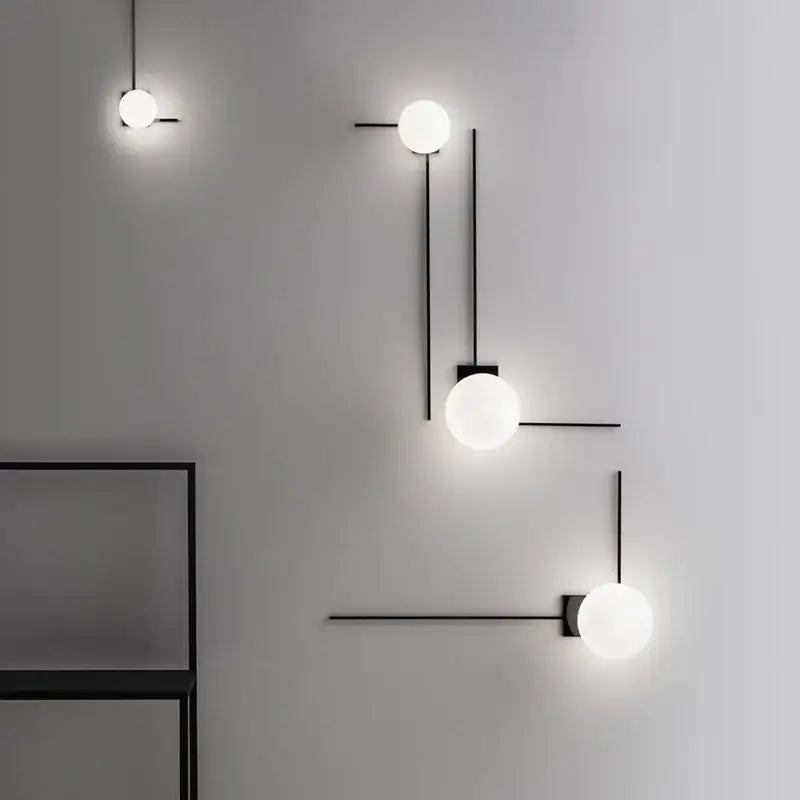 Modern minimalist black metal wall lights with frosted white glass ball shades ideal for bedroom lighting