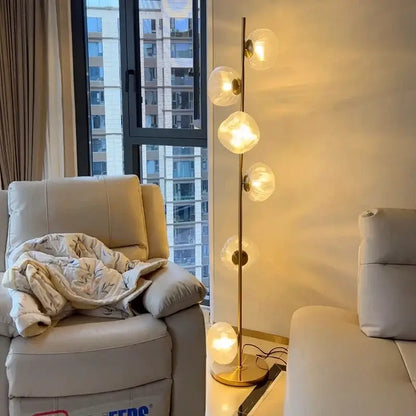 Modern minimalist floor lamp with slender gold-toned metal stand and five warm glass shade led globes for home decor