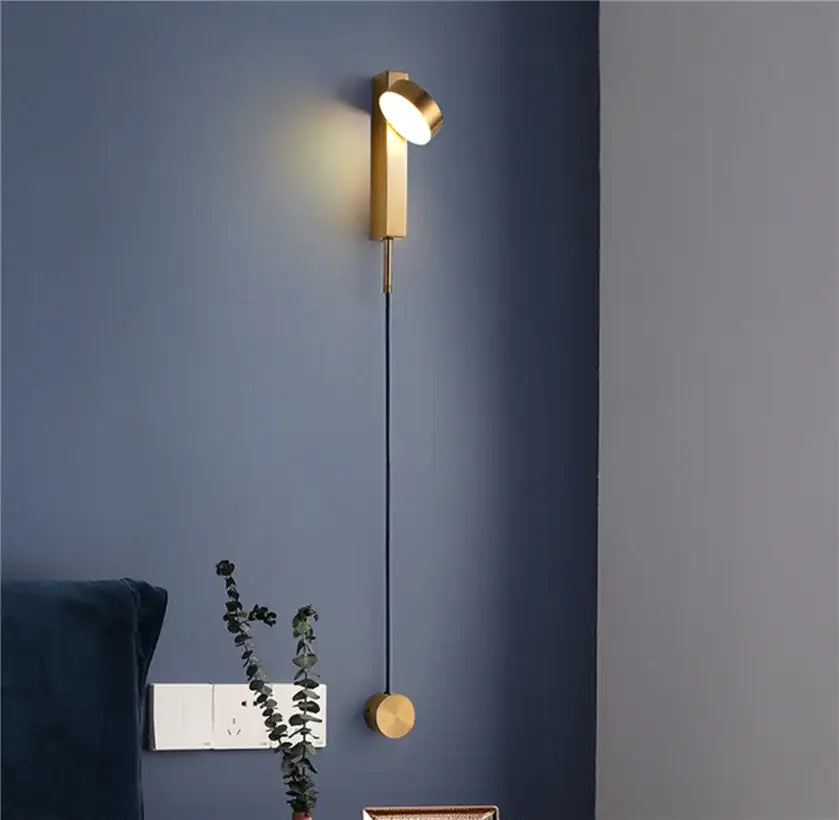 Gold-toned adjustable modern minimalist wall light sconce with black cord for bedroom wall light installation