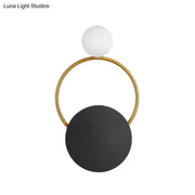 Modern minimalist black and gold wall light with a gold circular frame, matte white bulb, and large black disc for bedroom use
