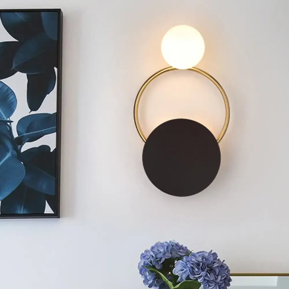 Modern minimalist black and gold wall light with a gold circular frame and two spherical shades for bedroom use