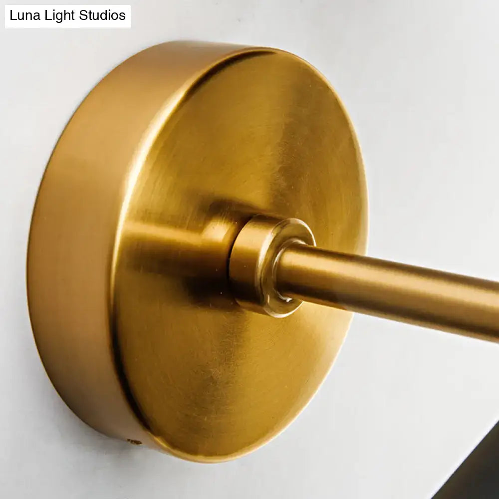 Brass-finished modern minimalist wall light fixture with circular base and cylindrical arm for bedroom sconce lighting