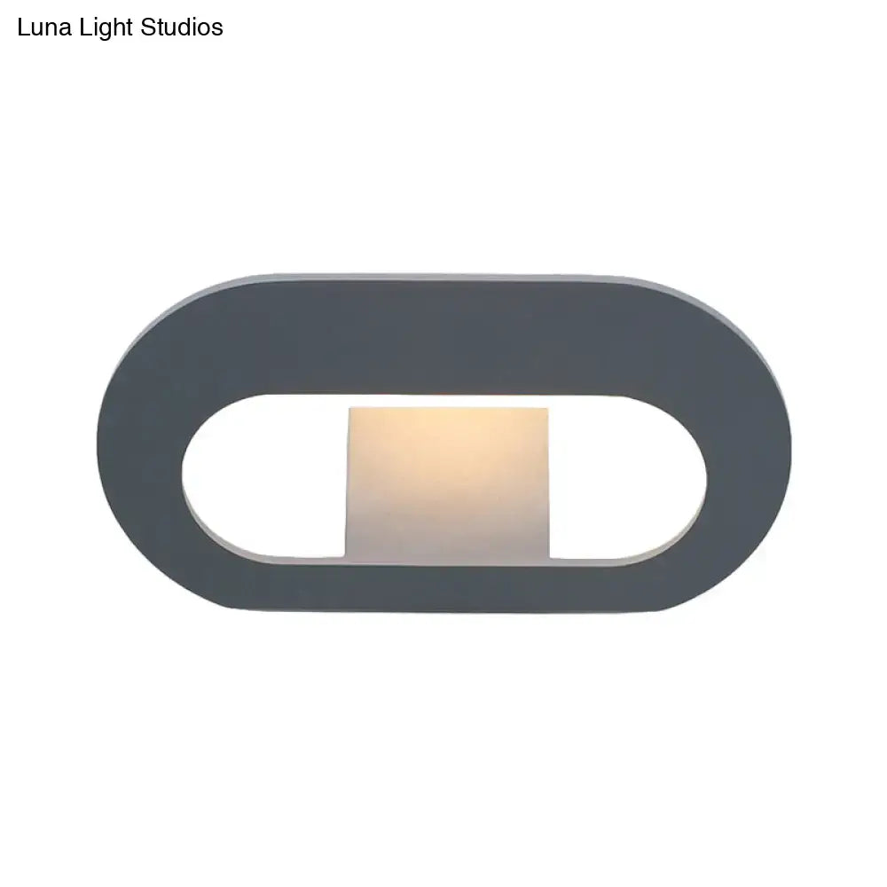 Modern minimalist wall lamp with oval shade and dark gray frame featuring warm softly glowing light panel for bedroom lighting