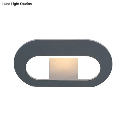 Modern minimalist wall lamp with oval shade and dark gray frame featuring warm softly glowing light panel for bedroom lighting