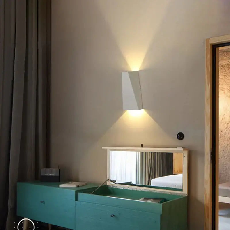 Modern minimalist black led wall lamp with a white geometric wall sconce casting warm light for bedroom reading