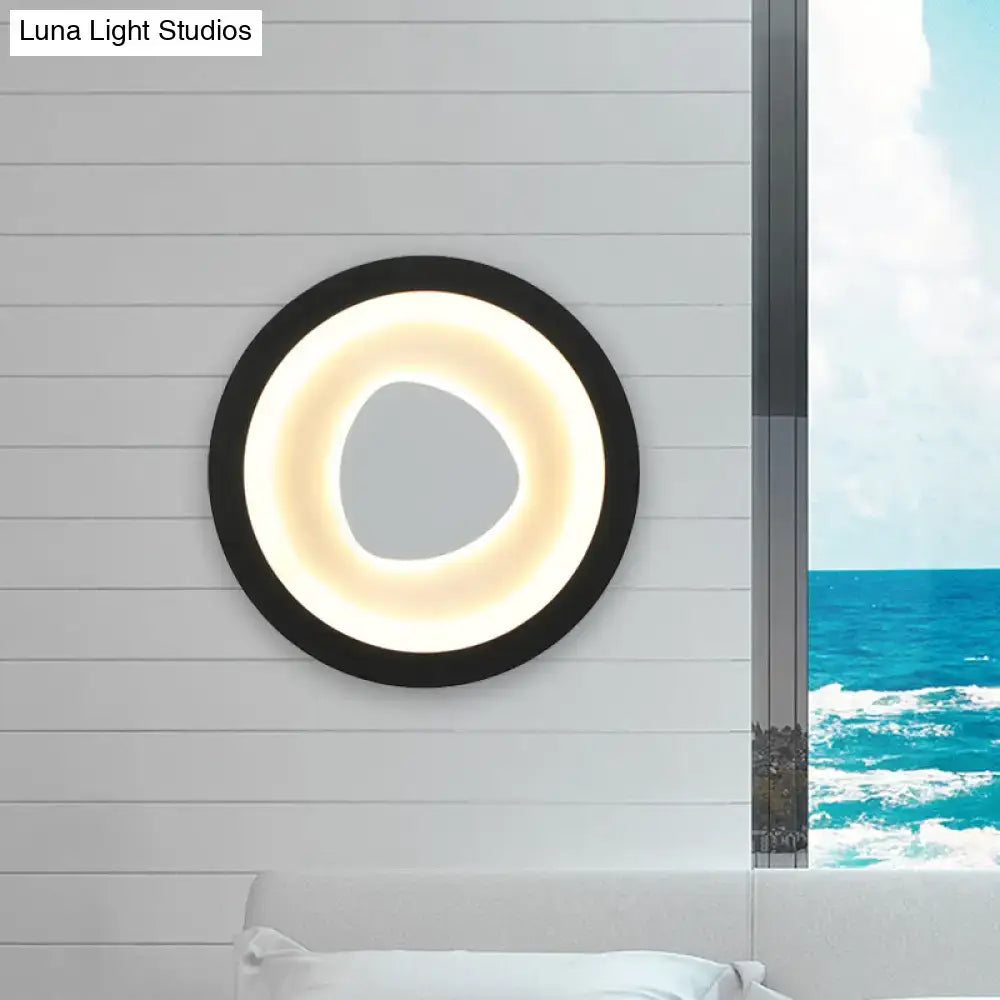 Modern minimalist black wall light with acrylic shade featuring a glowing ring and irregular central cutout for bedroom