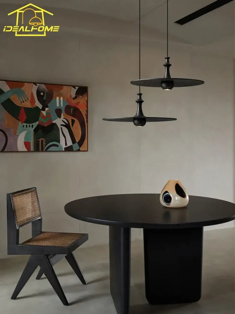 Cream-colored ceramic sculpture with black cutout details on dark table complements decorbites black solid wood pendant lights
