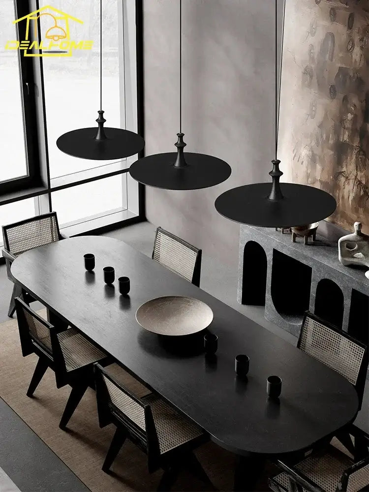 Modern minimalist black solid wood pendant lights above a black matte-finished oval dining table with integrated seating