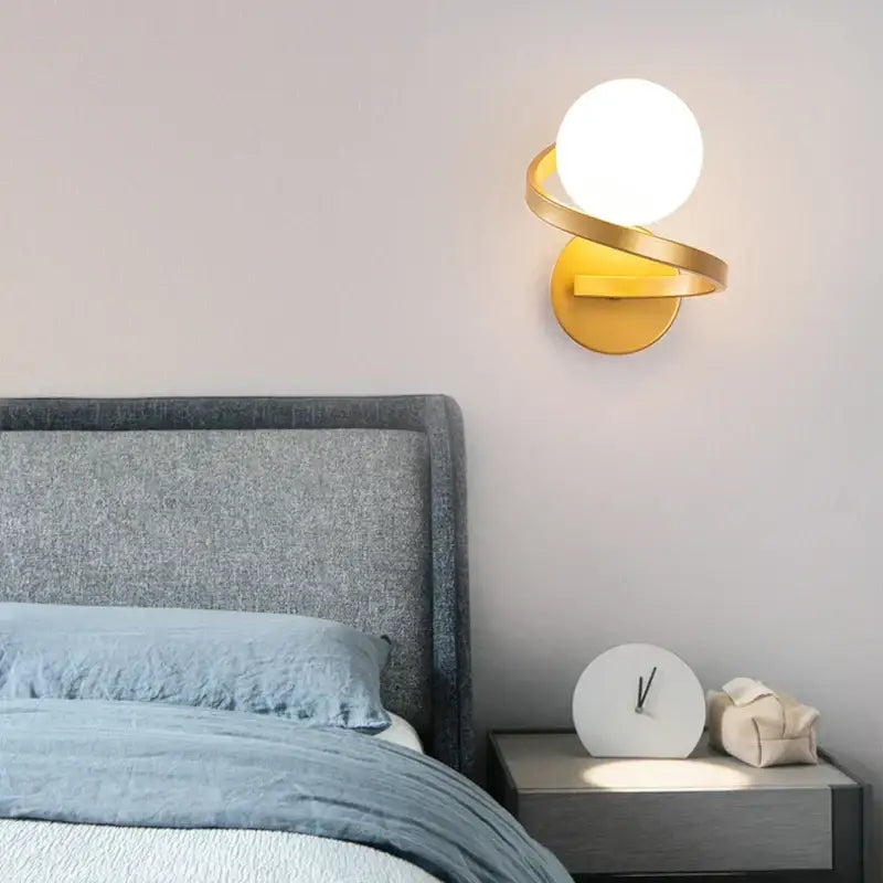 Gold-toned wall lamp with frosted glass ball and curved metallic arms modern minimalist led wall lamp for bedroom