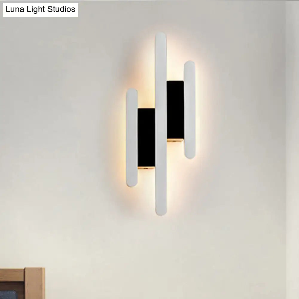 Modern minimalist black and white led wall sconce with three vertical bars emitting warm white light for bedrooms