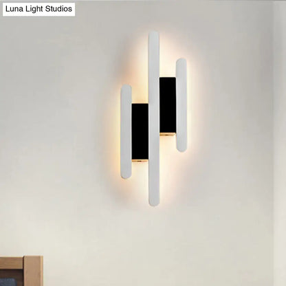 Modern minimalist black and white led wall sconce with three vertical bars emitting warm white light for bedrooms