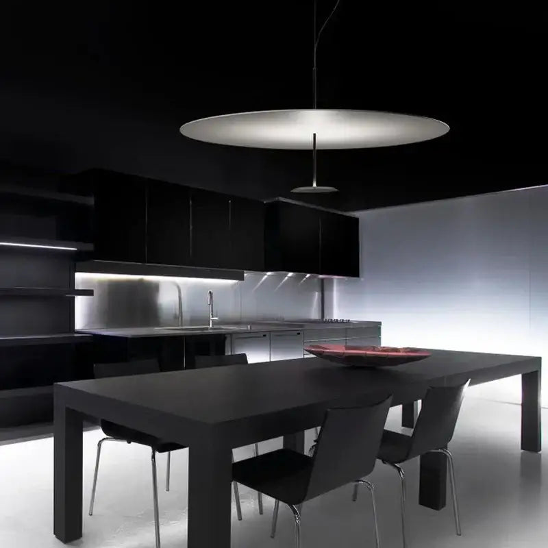 A modern minimalist black and white saucer pendant light with matte white diffuser and thin black cord pendant installation