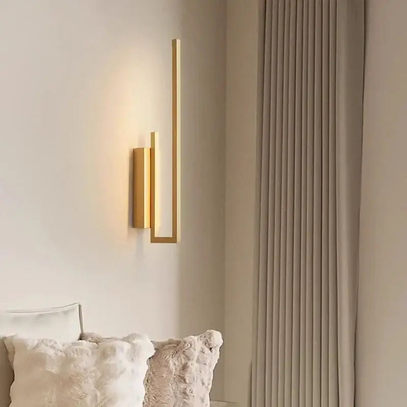 Modern minimalist brushed bronze and gold brass wall sconce with sleek vertical bars and warm ambient glow for bedroom decor