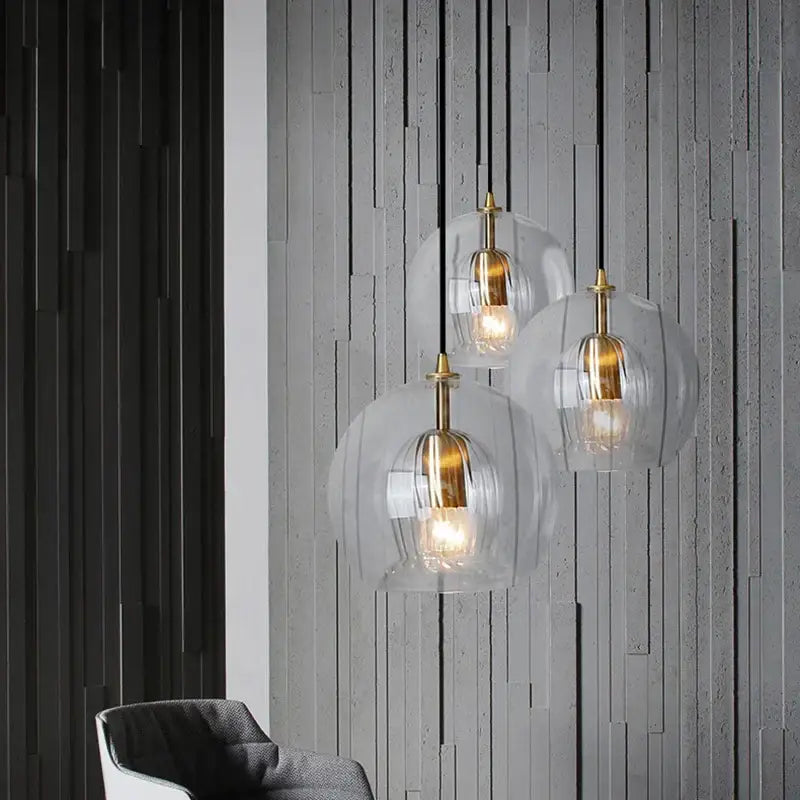 Three modern pendant lights with clear glass ball domes and brass accents for dining room decorbites clear glass