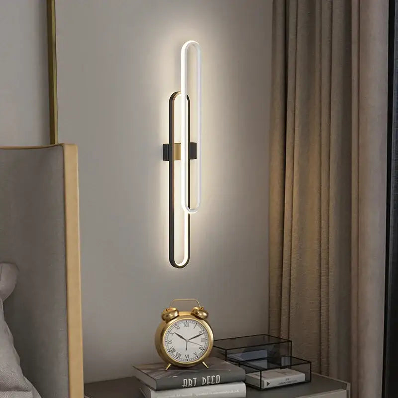 Modern minimalist decorbites led wall sconce with sleek oval design, matte black metal frame, brushed gold accents, warm white light