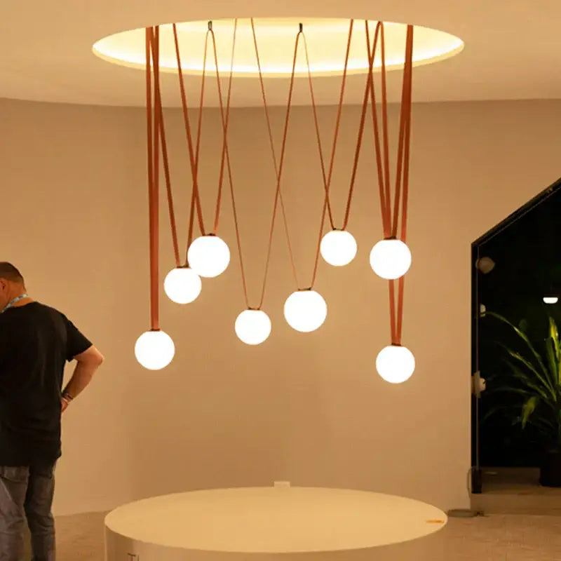 Modern minimalist frosted glass ball pendant light with seven white bulbs suspended by leather cords for dining room decorbites glass ball