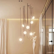 Modern minimalist pendant light with multiple frosted glass ball bulbs suspended by dark metal cords for dining room decorbites glass ball