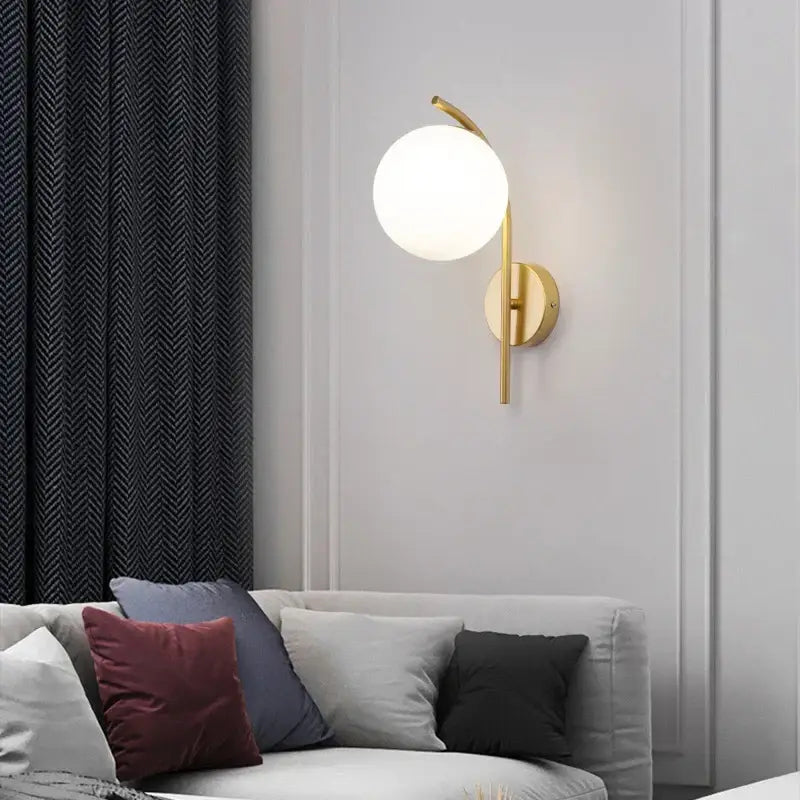 Gold-toned modern minimalist wall lamp with spherical frosted glass shade and sleek curved metal arm led wall lamp